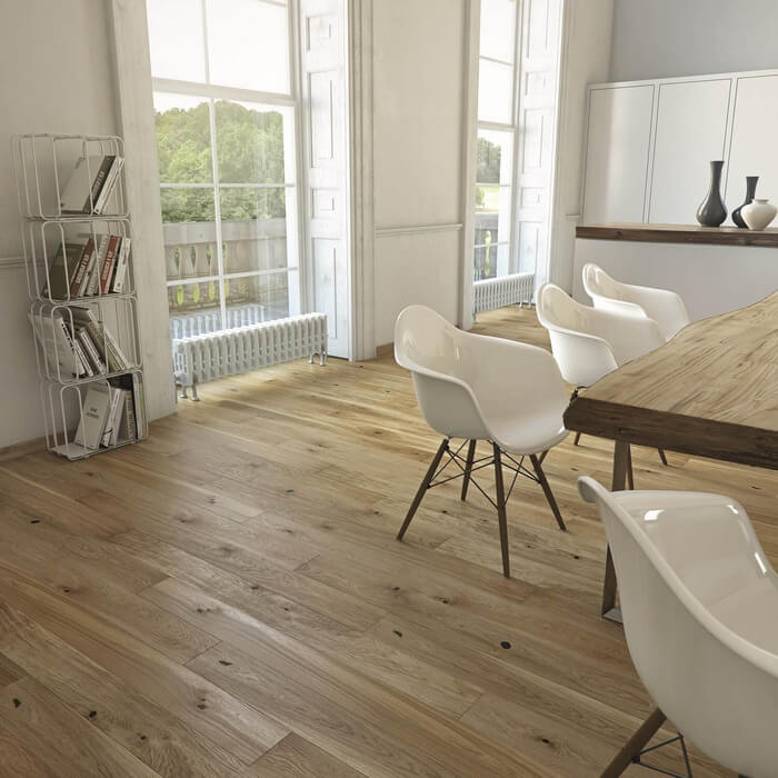 A stylish dining room with wooden flooring and white walls with a wooden table and plastic chairs