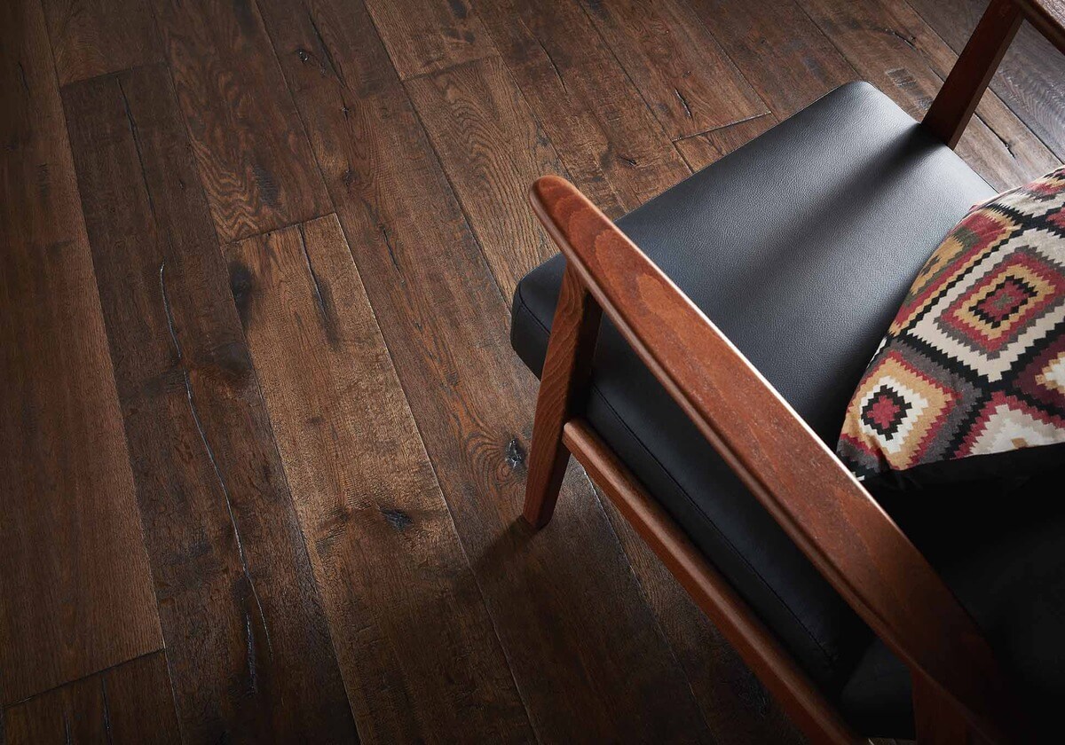 A wooden armchair with cushions on a dark wooden floor