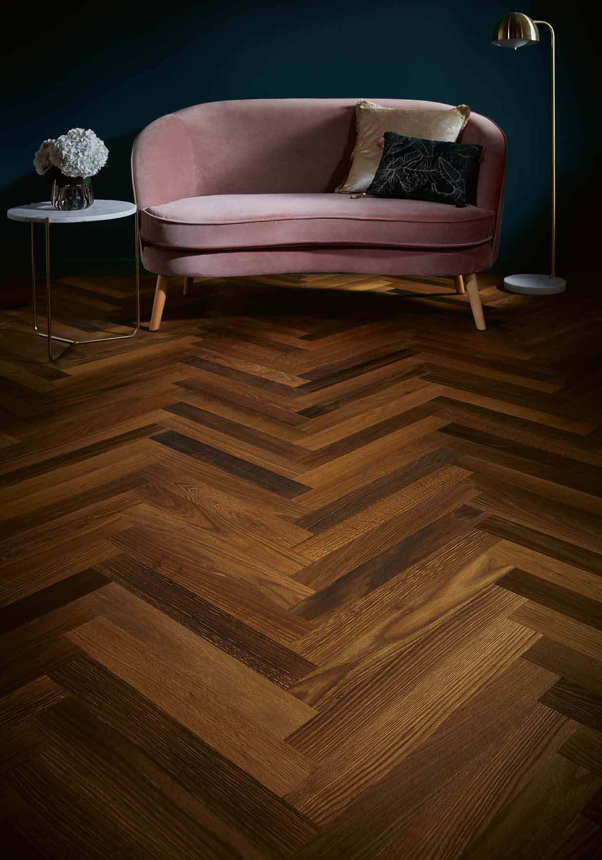 Dark parquet flooring with a light pink sofa